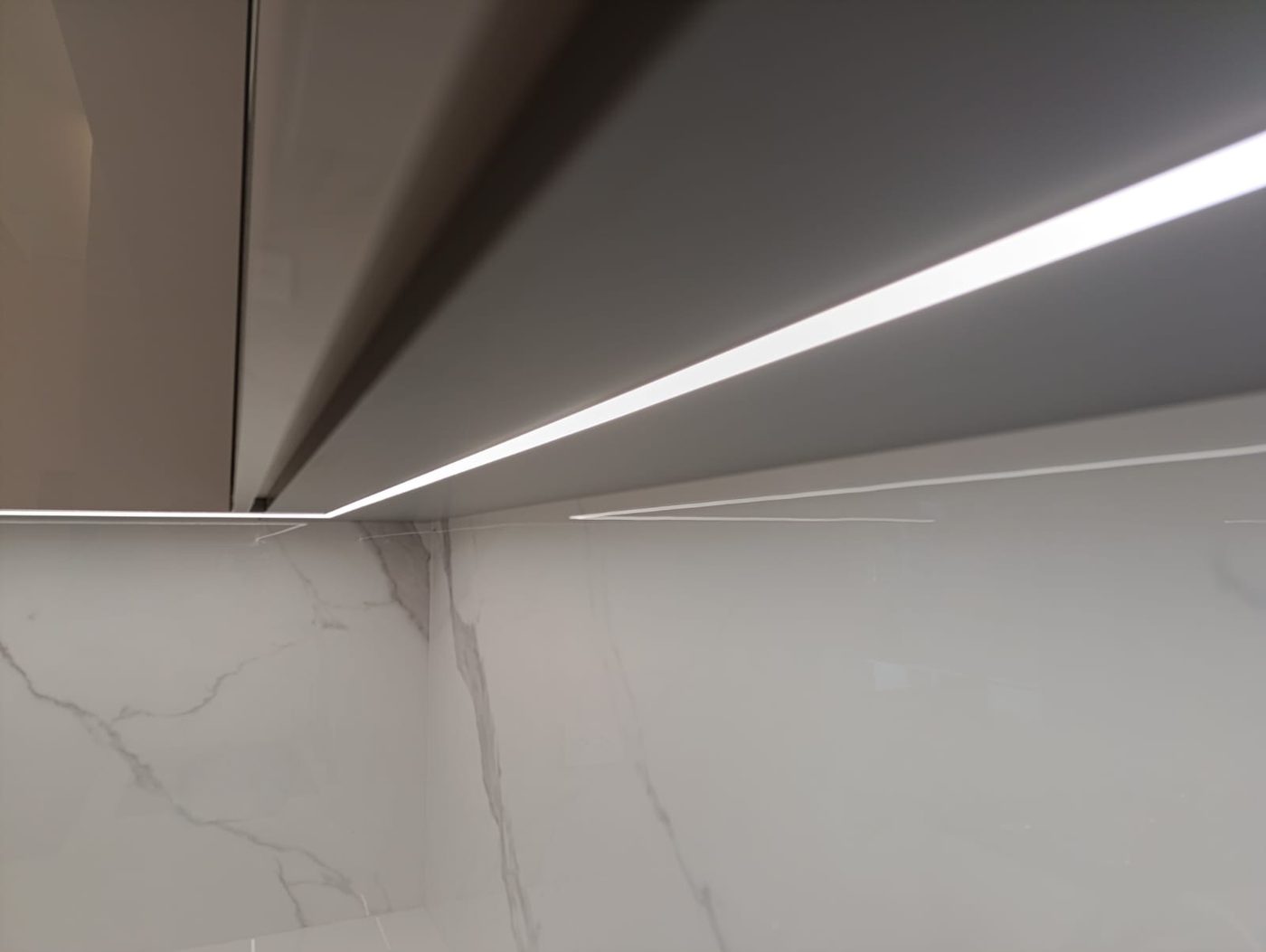 Iluminación LED bajo mueble de cocina con respaldo en mármol
